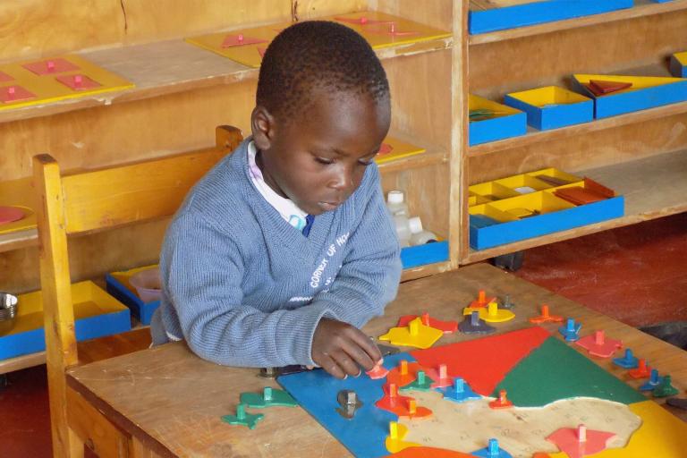 Boy with puzzle map at Corner of Hope Montessori